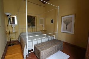 1 dormitorio con cama con dosel y banco de mimbre en Podere Il Trebbio, porzione di villa, en Gaiole in Chianti