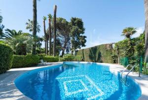 a large blue swimming pool with trees and palm trees at Cannes Events, Beach, Pool & Parking in Cannes