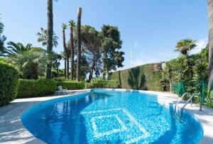 a large blue swimming pool with trees and palm trees at Sea Side apartment in Cannes