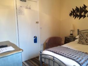 Schlafzimmer mit einem Bett, einem Schreibtisch und einer Tür in der Unterkunft The Eagles Hotel in Llanrwst