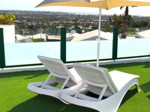 two white chairs and an umbrella on a roof at Vista Dorada 7A in Maspalomas