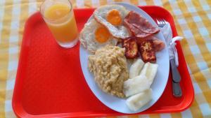 a red tray with a plate of breakfast food and a drink at Apartahotel Jardines Metropolitanos in Santiago de los Caballeros