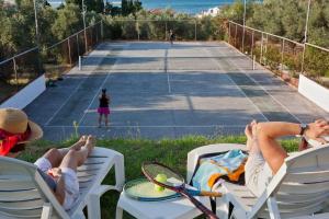 dos personas tumbadas en sillas en una pista de tenis en Del Sol Skopelos, en Skopelos Town