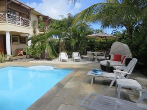 a swimming pool with chairs and an umbrella next to a house at Villa Kreola in Grand Gaube