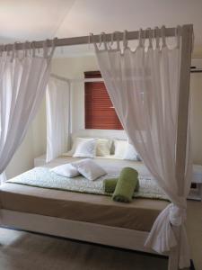 a bed with white curtains in a bedroom at Villa Kreola in Grand Gaube