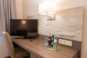 a desk with a computer monitor and drinks on it at Hotel Westermann in Osnabrück