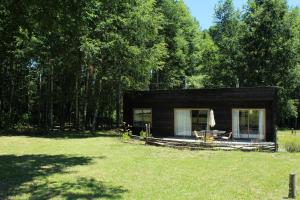 a small black cabin in the middle of a yard at Cabañas Am Berg in Pucón