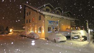 a snow covered yard with cars parked in front of a building at Hotel Alpin in Ehrwald