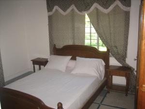 a bedroom with a bed with two night stands and a window at Farida Lodge in Moroni