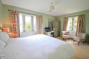 a bedroom with a large white bed and two windows at Oxbridge Farm in Netherbury