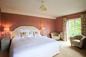 a bedroom with a large white bed and a chair at Oxbridge Farm in Netherbury