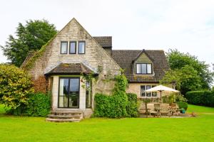 a stone house with a table and an umbrella at Oxbridge Farm in Netherbury