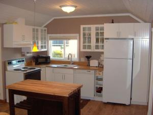 Historic 1920s Cabin في لونغ بيتش: مطبخ فيه دواليب بيضاء وثلاجة بيضاء