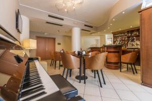 restauracja z fortepianem, stołem i krzesłami w obiekcie UNA HOTELS Occhiobello w mieście Occhiobello