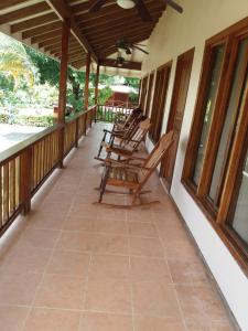 a row of rocking chairs on the porch of a house at La Perla in Pavones
