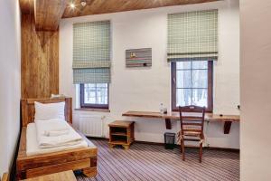 a bedroom with a bed and a desk and two windows at Shpatser hotel in Briukhovychi