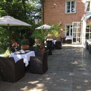 a patio with tables and chairs and an umbrella at Hotel B&B Bredl in der Villa Ballestrem in Straubing