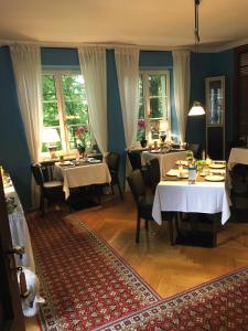 een eetkamer met tafels, stoelen en ramen bij Hotel B&B Bredl in der Villa Ballestrem in Straubing