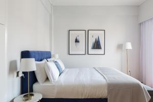een witte slaapkamer met een bed en drie foto's aan de muur bij Central Cozy Apartments in Plaka by UPSTREET in Athene