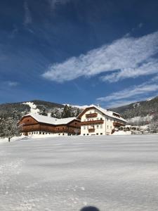 un grand bâtiment avec de la neige sur le sol devant dans l'établissement Niederhaeusererhof, à Falzes