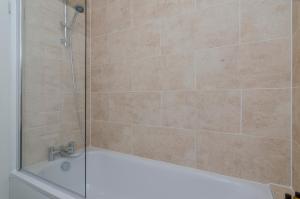 a shower with a glass door and a tub at Saffron - Heathrow-Airport-with Parking in Feltham