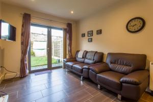 a living room with two leather couches and a clock at The Artane Self Catering in Dublin