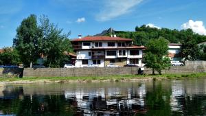 a house with cars parked in front of a river at Family Hotel and Restaurant Varosha 2003 in Lovech