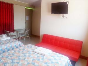 um quarto com duas camas e um sofá vermelho em Pisco Hotel Corina em Pisco