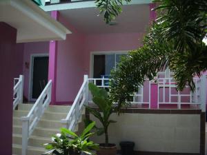 ein rosafarbenes Haus mit Treppen und Pflanzen davor in der Unterkunft Baan Kaneang in Ko Larn