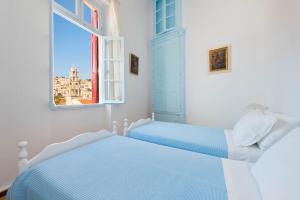 2 Betten in einem weißen Zimmer mit Fenster in der Unterkunft Castello Venetsiana in Symi