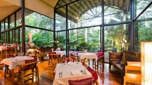 a restaurant with tables and chairs and large windows at Pethers Rainforest Retreat in Mount Tamborine