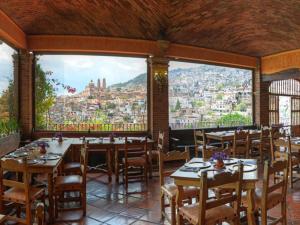 a restaurant with tables and a view of a city at Posada de la Mision, Hotel Museo y Jardin in Taxco de Alarcón