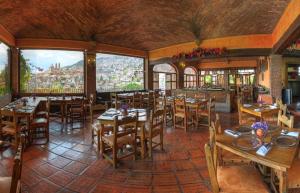 a restaurant with wooden tables and chairs and windows at Posada de la Mision, Hotel Museo y Jardin in Taxco de Alarcón