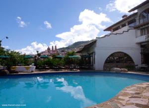 a large blue swimming pool in front of a building at Posada de la Mision, Hotel Museo y Jardin in Taxco de Alarcón