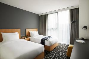 a hotel room with two beds and a window at L7 Gangnam by LOTTE in Seoul
