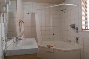 a white bathroom with a tub and a sink at Victoria Court Motor Lodge - Free Parking in Wellington +34 photos