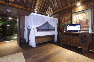 a bedroom with a bed and a desk with a television at Honeymoon Green Villa in Ubud