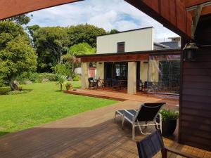 a deck with chairs and a house at Heta Road B&B in New Plymouth