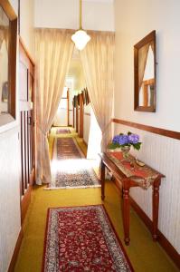 Un pasillo con alfombras y una mesa con flores. en Braemar House B&B and YHA Hostel, en Whanganui