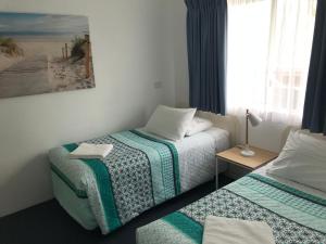 1 dormitorio con 2 camas individuales y ventana en Aquarius Apartments Mollymook en Mollymook
