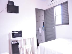 Pousada Chapada das Mesas في Riachão: غرفة بيضاء بسرير وطاولة ونافذة