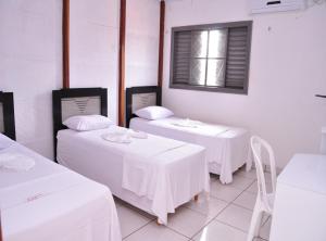Habitación blanca con 2 mesas y ventana en Pousada Chapada das Mesas, en Riachão