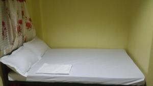 - une petite chambre avec un lit blanc dans l'établissement RMS Travellers Inn, à Îles Camotes