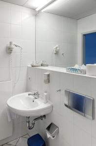 a white bathroom with a sink and a mirror at Opera Hotel Köln in Cologne