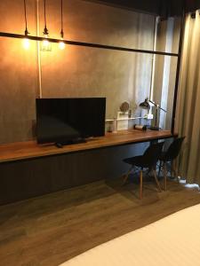 a bedroom with a desk with a television and a chair at Bedgasm Hostel Chanthaburi in Chanthaburi