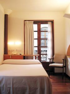 um quarto com uma cama, uma secretária e uma janela em La Plaza I em Luanco