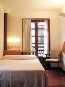 a bedroom with a bed and a desk and a window at La Plaza I in Luanco