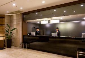 2 persone sedute al bancone nella hall di un hotel di Kawasaki Nikko Hotel a Kawasaki