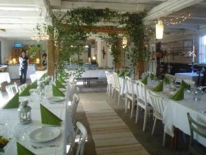 a dining room with white tables and chairs with green napkins at Brunnsta Gård in Bålsta