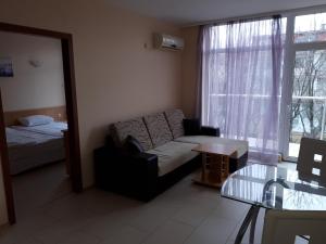 een woonkamer met een bank, een bed en een raam bij Apart Hotel Ravda in Ravda